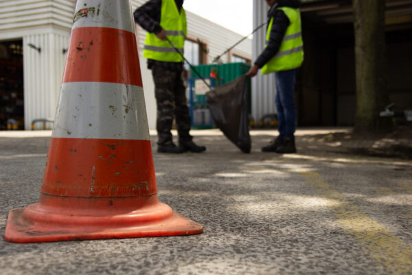 werkgestraften prikken vuil in een vuilniszak met een pion op de voorgrond