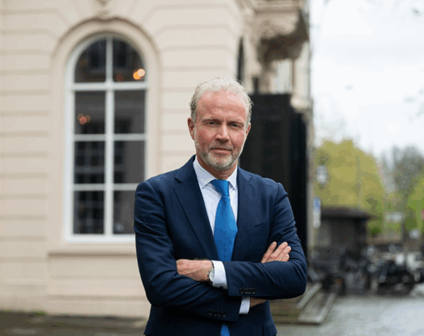 Portret directielid Johan Bac met armen over elkaar heen, buiten voor een gebouw