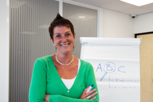 lachende vrouw met kort haar, een groene top en haar armen over elkaar