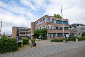 roodbruin gebouw langs het voetenpad en auto weg, omringd door struiken