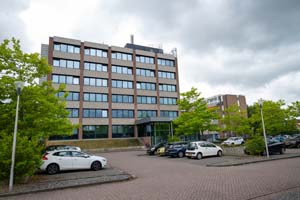 Hoog flatgebouw met een parkeerplaats voor de deur