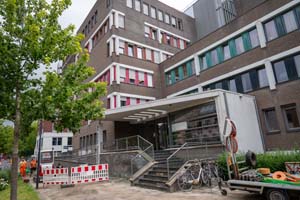 Bruin gebouw met rode omlijning op de ramen